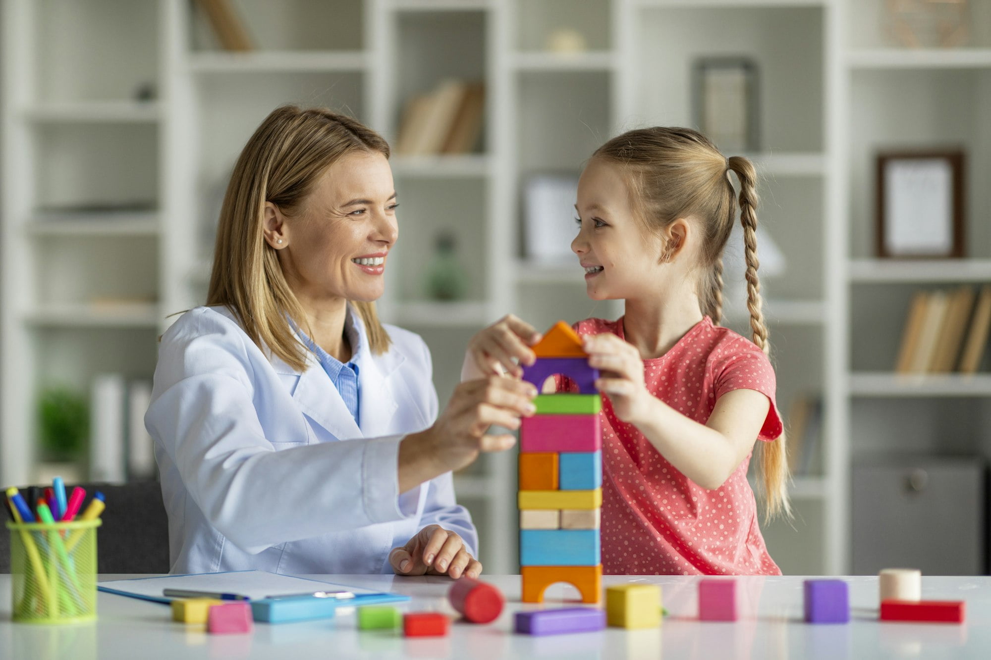 Play Therapy. Little Girl And Child Development Specialist Playing Wooden Bricks Together